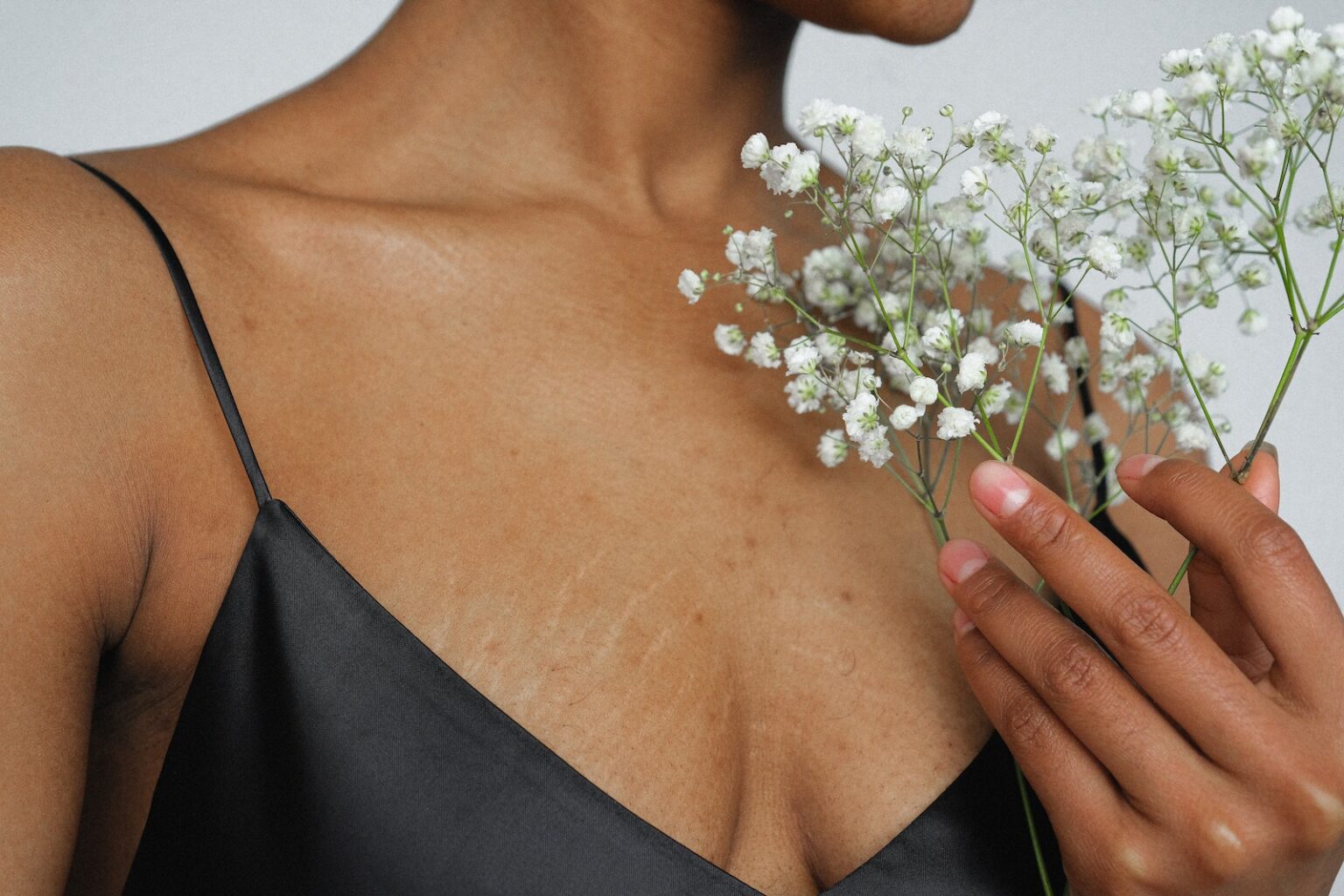 Woman in Black Spaghetti Strap Top Holding White Flowers