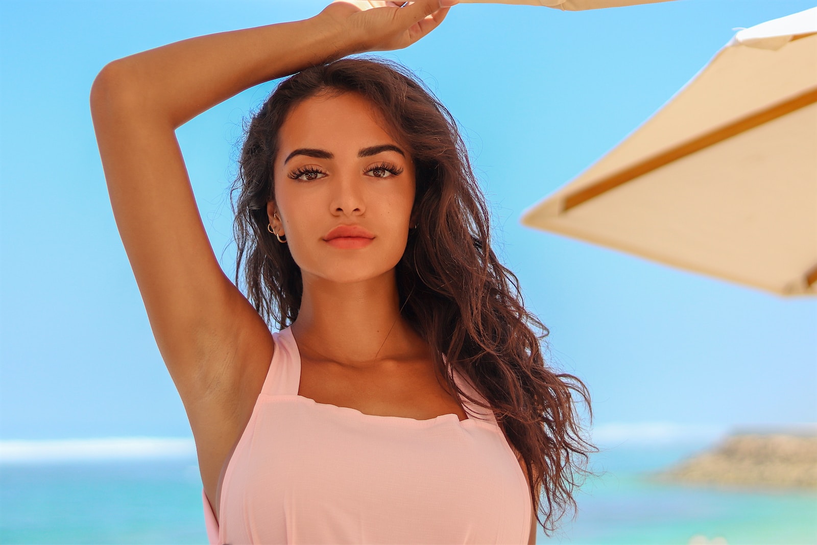 woman in white spaghetti strap top holding her hair