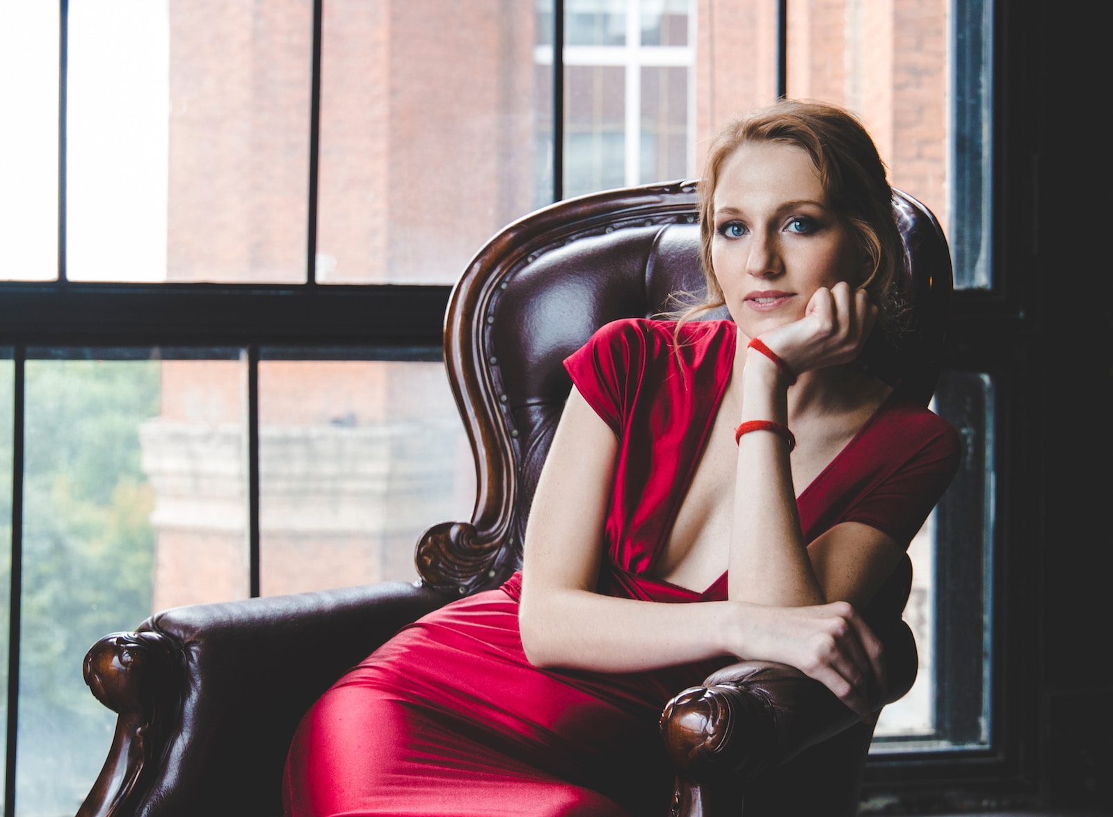 woman in black sleeveless dress sitting on black leather couch